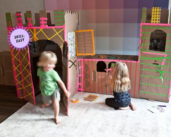a child playing inside a cardboard box castle